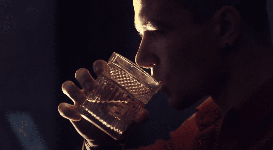 Мужчина пьёт алкоголь из стакана